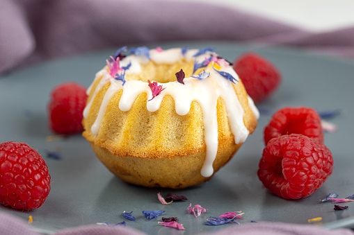 homemade fresh baked sponge cake with white icing and colorful blossoms, gugelhupf, close up