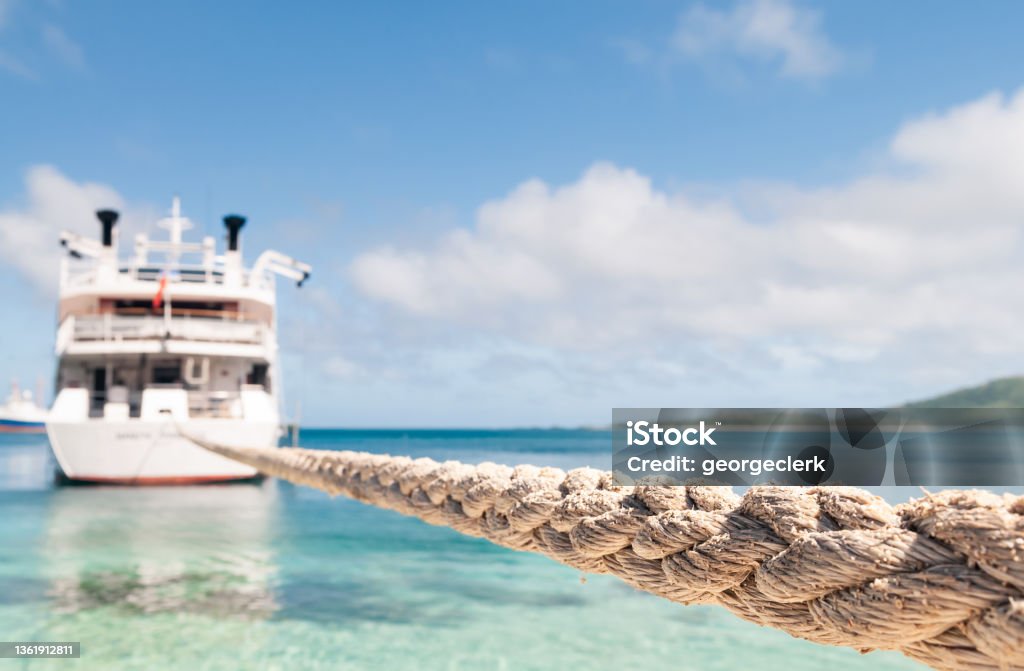 Tight rope securing boat A long rope holding a boat moored off a beach in Fiji. Close-up focus on the foreground rope, with the boat defocused. Rope Stock Photo