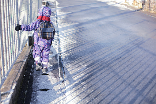 Asian boy walking to school in the morning with snow. Beautiful winter morning.