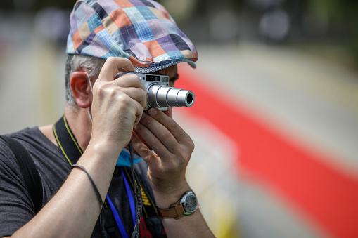 Braila, Romania - August 26, 2021:Shallow depth of field (selective focus) details with a man taking pictures with a small compact camera.