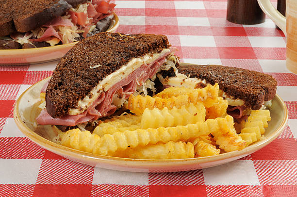 Reuben Sandwich A corned beef sandwich with fries on a picnic table reuben sandwich stock pictures, royalty-free photos & images