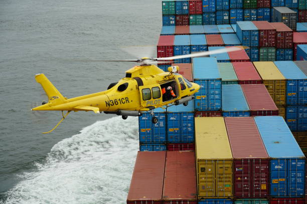 fliegender gelber hubschrauber mit columbia river bar pilot über containern, die für die überführung von piloten bereit sind. - piloting commercial dock harbor industrial ship stock-fotos und bilder