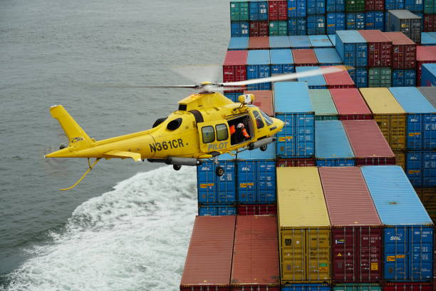 hélicoptère jaune volant avec le pilote columbia river bar au-dessus de conteneurs prêts pour le transfert des pilotes. - piloting commercial dock harbor industrial ship photos et images de collection