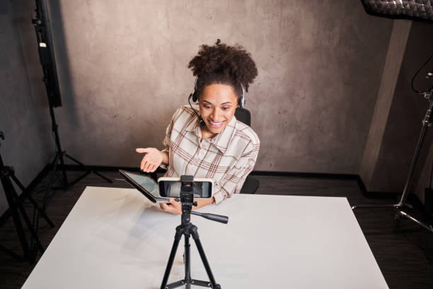 istock Multiracial woman making a video for her blog using tripod mounted digital camera 1361925252