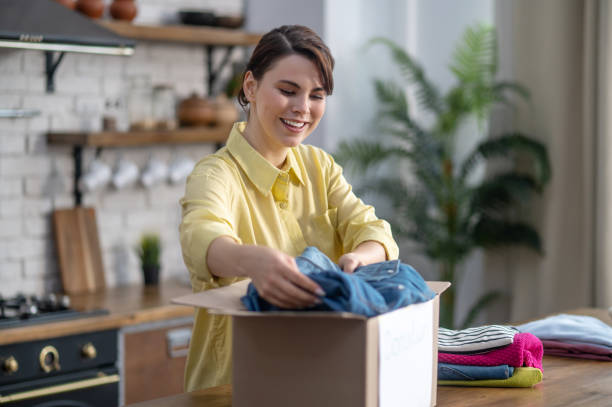 istock Joyful lady packing sorted clothes into a carton 1361926090