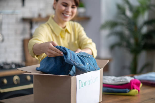 istock Focused contented female packing clothes for donation 1361926091