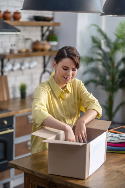 istock Concentrated young female packing clothes within the carton 1361926097