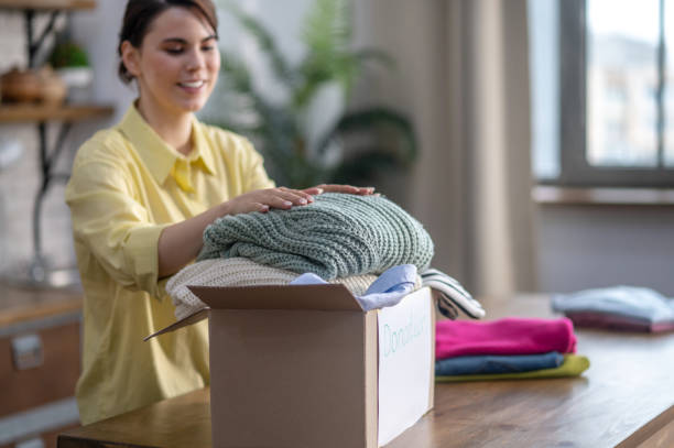 Happy lady placing sweaters in the carton stock photo