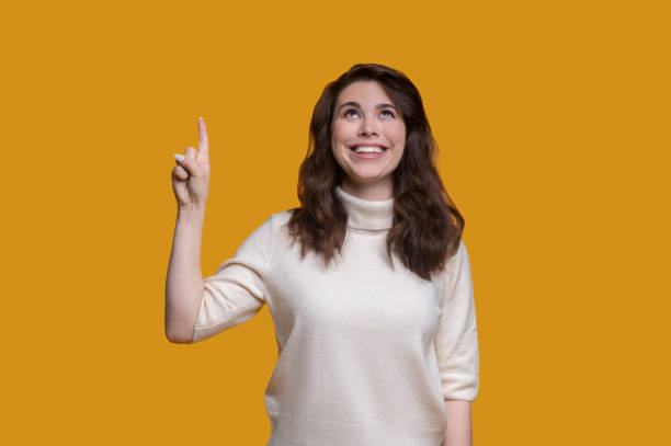 istock Joyous lady with the lifted forefinger looking upwards 1361926115
