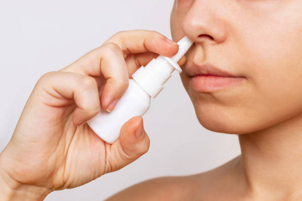 Cropped shot of a young caucasian woman using nasal spray for a runny nose and congestion Cropped shot of a young caucasian woman using nasal spray for a runny nose and congestion isolated on a white background. Treatment of the disease. Rhinitis, sinusitis, cold. Dependence on drops nasal spray stock pictures, royalty-free photos & images
