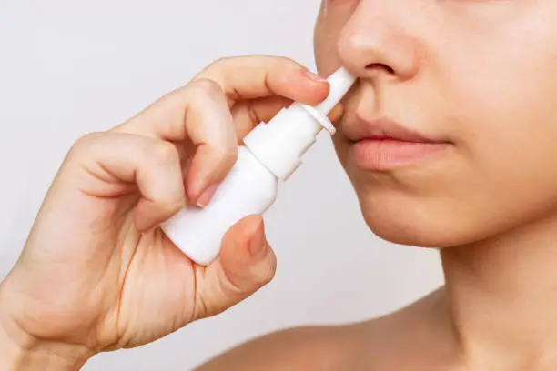 Photo of Cropped shot of a young caucasian woman using nasal spray for a runny nose and congestion