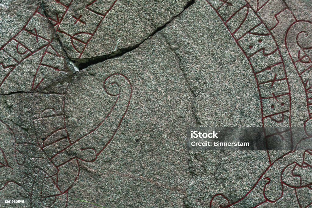 Close up of a cracked rune stone with red runes Background texture from a detailed close up of an old cracked rune stone with red runes Viking Stock Photo