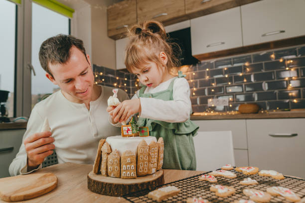 istock Father and daughter decorated gingerbread cake in the kitchen 1361934038