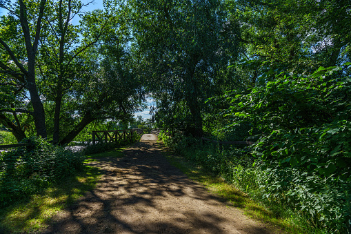 Beautiful summer view from a path with an upcoming crossing bridge, passing through a lush green landscape in Sweden