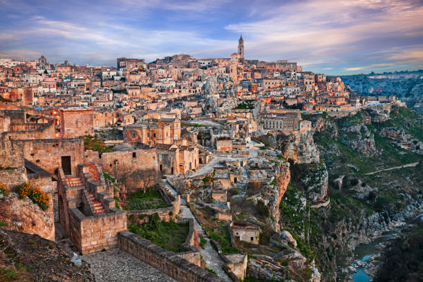 matera, basilicata, italia: paisaje al amanecer del casco antiguo llamado sassi con las antiguas casas cueva y el arroyo en el fondo del profundo barranco - deep creek area fotografías e imágenes de stock