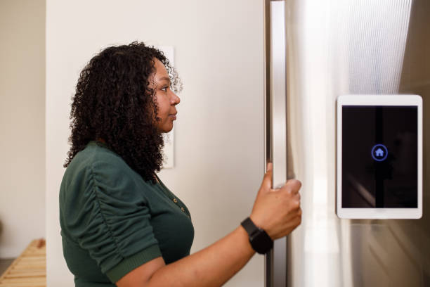 istock Woman looking into the fridge while it shows information on an attached tablet at the door 1361939972