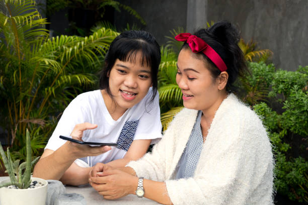 istock Thai daughter with mother is sitting at table with mobile 1361940356