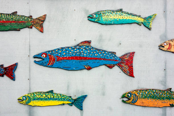 A series of different salmon speciss in colorful paint are posted on the plywood wall of a fish market in the San Juan Islands.