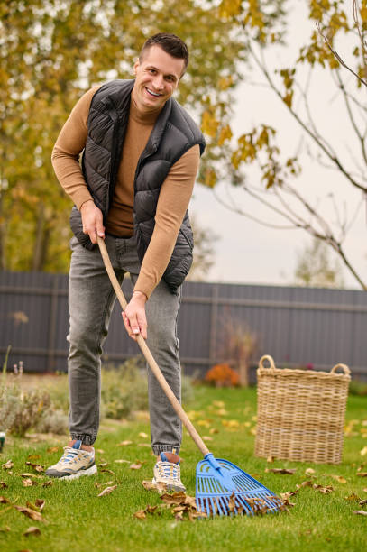 istock Man with rake cleaning leaves looking at camera 1361941033