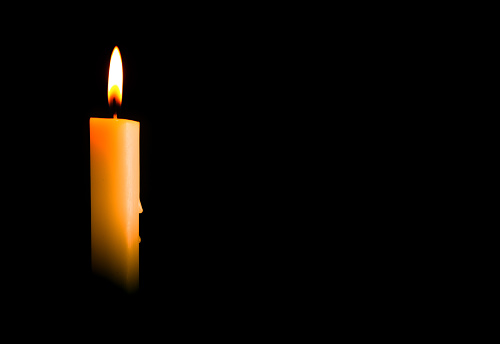 Candle light burning brightly in the black background, blank and wide background for copy space.