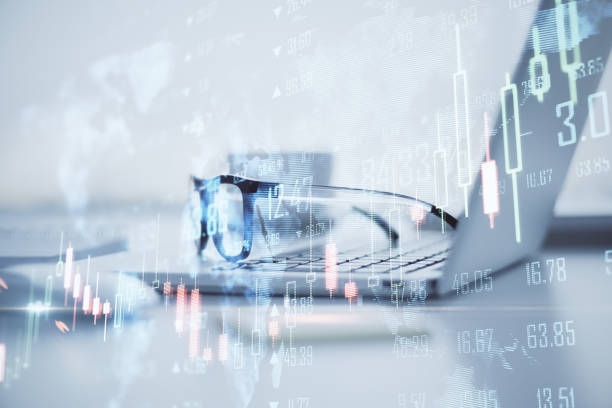 istock Close up of laptop and glasses with map, creative glowing big data forex chart candlestick hologram on blurry office background. Trade, technology and finance concept. Double exposure. 1361958108