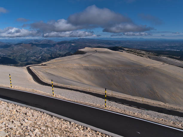 View over the bare summit of Mont Ventoux, consisting of white limestone rock, in Provence region, France with paved country road D974 and panoramic view over the Prealps. View over the bare summit of Mont Ventoux, consisting of white limestone rock, in Provence region, France with paved country road D974 and panoramic view over the Prealps on sunny day in autumn. mistral wind stock pictures, royalty-free photos & images