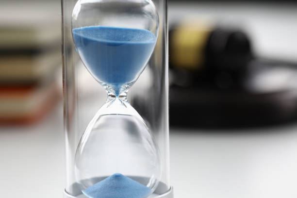 istock Close-up of hourglasses with blue sand inside standing on table 1361962916