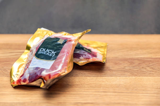 vacuum packed duck breast. duck meat in vacuum plastic packaging on a wooden cutting board, background for a culinary theme, place for text - packing duck imagens e fotografias de stock