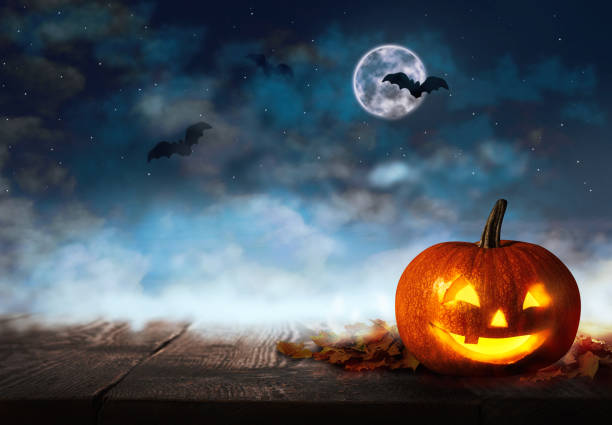 istock Spooky Jack O Lantern pumpkin under dark sky with flying bats and full moon on Halloween night. Space for text 1361965659