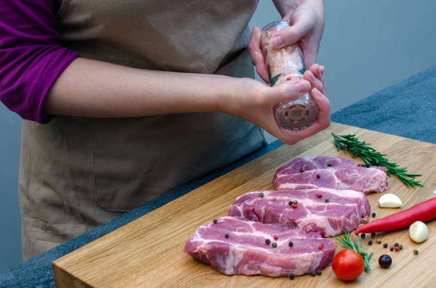 istock Chef prepares meat steak and adds salt and pepper on gray background, copy space for restaurant menu or recipe text 1361966166