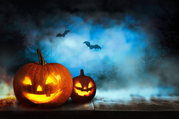 istock Scary Jack O Lantern pumpkins and flying bats in misty forest on Halloween. Space for text 1361968146