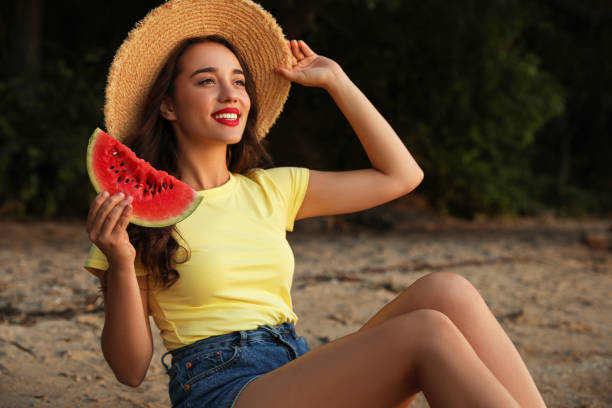 istock Beautiful young woman with watermelon on sandy beach 1361968152