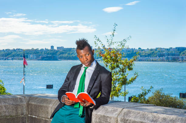 un joven negro con corte de pelo mohawk está parado junto a un río, leyendo, pensando". r - mohawk river fotos fotografías e imágenes de stock