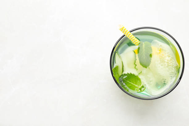 istock Refreshing water with cucumber, lemon and mint on white table, top view. Space for text 1361969131