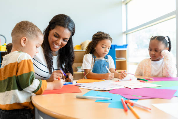 istock Art teacher smiles a preschool boy's drawing 1361969310