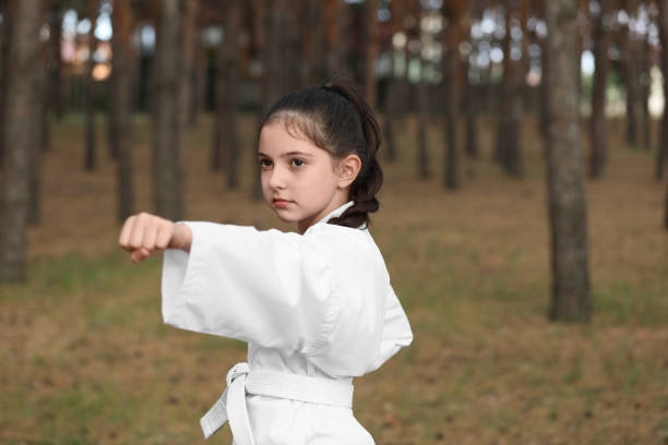 istock Cute little girl in kimono practicing karate in forest 1361969428