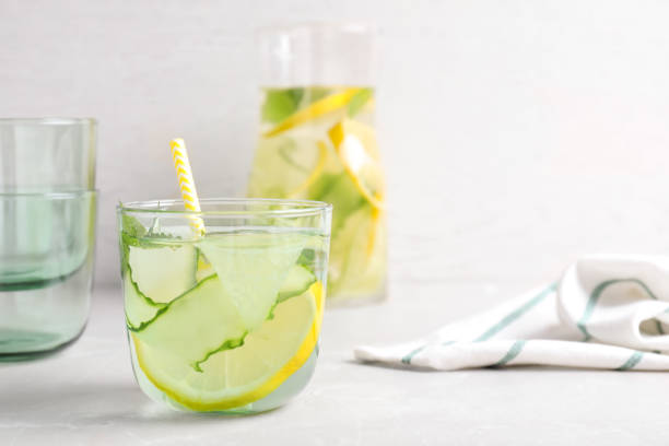 istock Refreshing water with cucumber, lemon and mint on white table 1361971749
