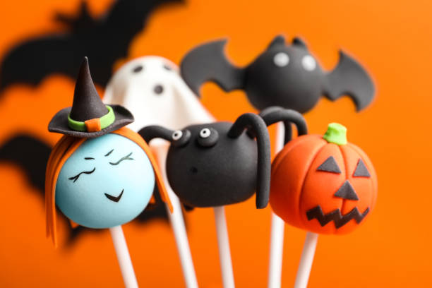 istock Delicious Halloween themed cake pops on orange background, closeup 1361977408