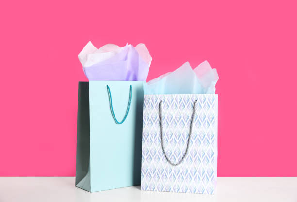 istock Gift bags with paper on white table against pink background 1361978772