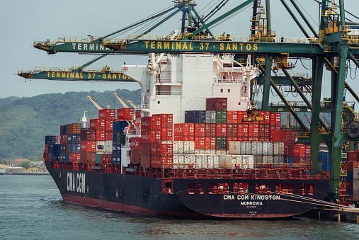 Container ship barge sailing on the Ramsdiep canal in Flevoland, Netherlands towards the IJsselmeer. The ship is carrying multiple containers stacked on the deck of the ship.