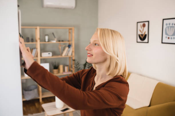 istock Happy young woman adjusting a smart system at her house 1361996989