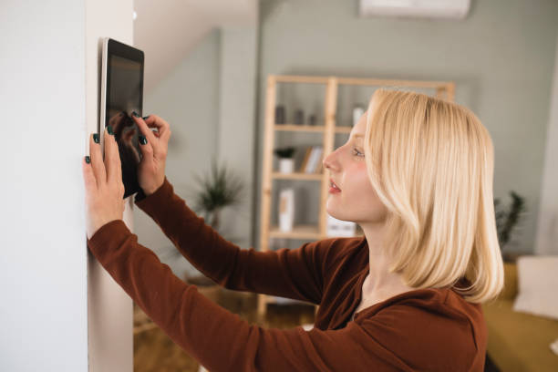 istock Young woman setting up the intelligent home system at her house 1361996990