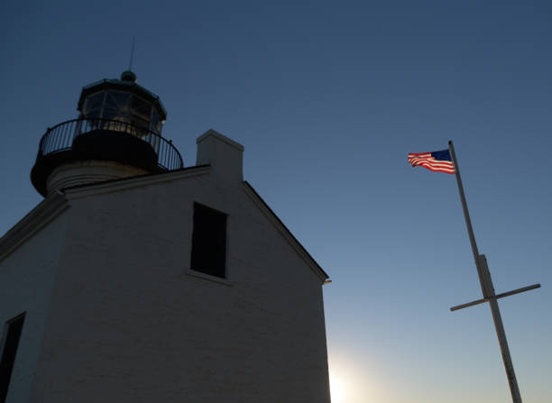 bandeira de americn sobre farol velho ao pôr do sol - naval flag - fotografias e filmes do acervo
