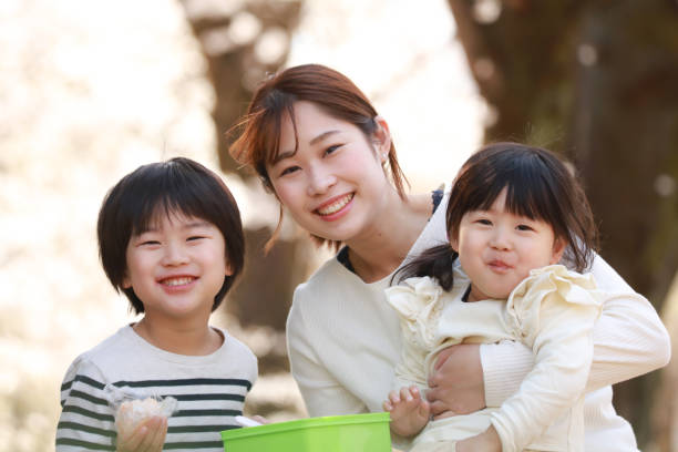 Japanese girl looking at mother and camera outdoors.