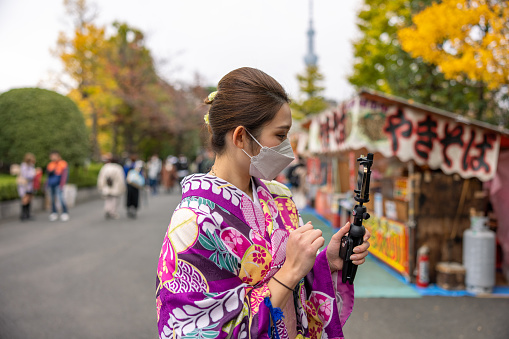 Young woman in kimono vlogging in matsuri