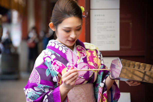 istock Young woman in kimono pulling a fortune slip 1362023903