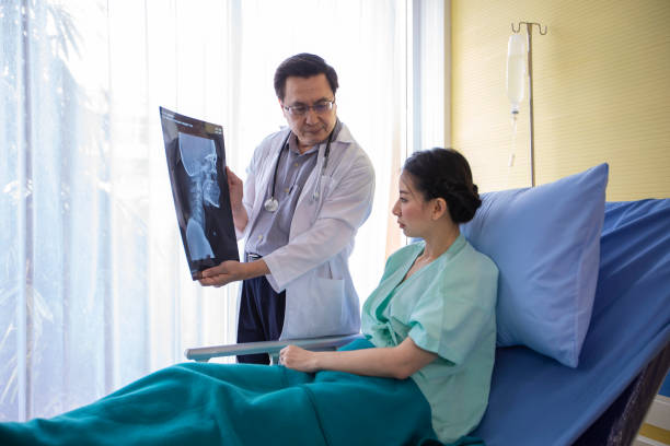 il medico sta spiegando i risultati dei raggi x del cervello a una paziente nel suo ufficio negli ospedali - doctor brain x ray x ray image foto e immagini stock