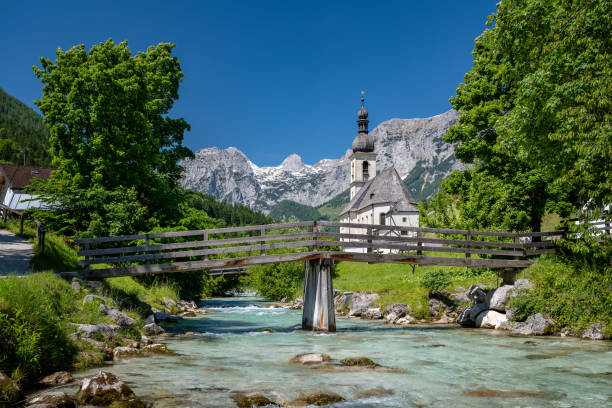 Idyllic St. Sebastian Church in Ramsau in summer, Bavaria, Germany View of the idyllic St. Sebastian church in Ramsau in summer, wooden bridge leads over a mountain stream, Bavaria, Germany upper bavaria stock pictures, royalty-free photos & images