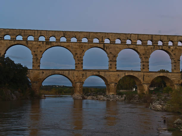 フランスのオクシタニーの町ヴェル・ポン・デュ・ガールの近くの夜にガルドン川にまたがる古代ローマの水道橋ポン・デュ・ガールの眺め。 - plumbing supplies ストックフォトと画像