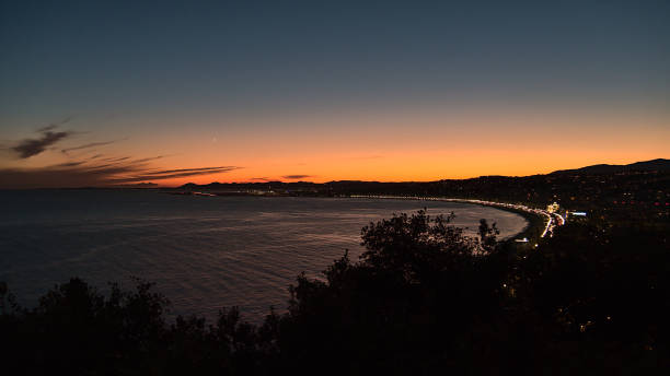 vista panoramica aerea sulla costa mediterranea della città di nizza, francia alla costa azzurra dopo il tramonto con spiaggia plage des ponchettes e illuminata promenade des anglais. - city of nice france french riviera promenade des anglais foto e immagini stock